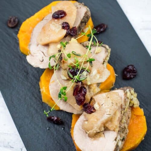 Serving of Slow Cooker Pork Tenderloin with Sweet Potatoes and Apples on a black platter.