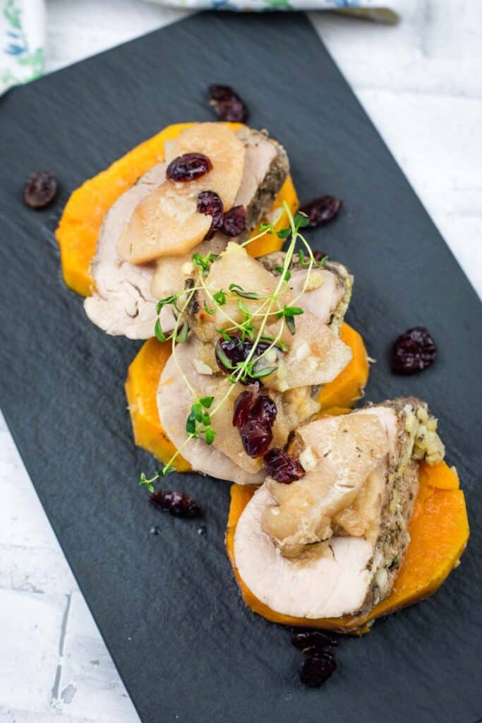 A serving of Slow Cooker Pork Tenderloin with Sweet Potatoes & Apples on a black platter.