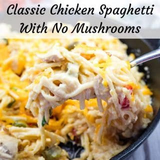 A fork with a serving of classic chicken spaghetti with no mushrooms from a cast-iron skillet.
