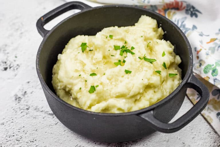 A black pot filled with Creamiest mashed potatoes, topped with chopped parsley.