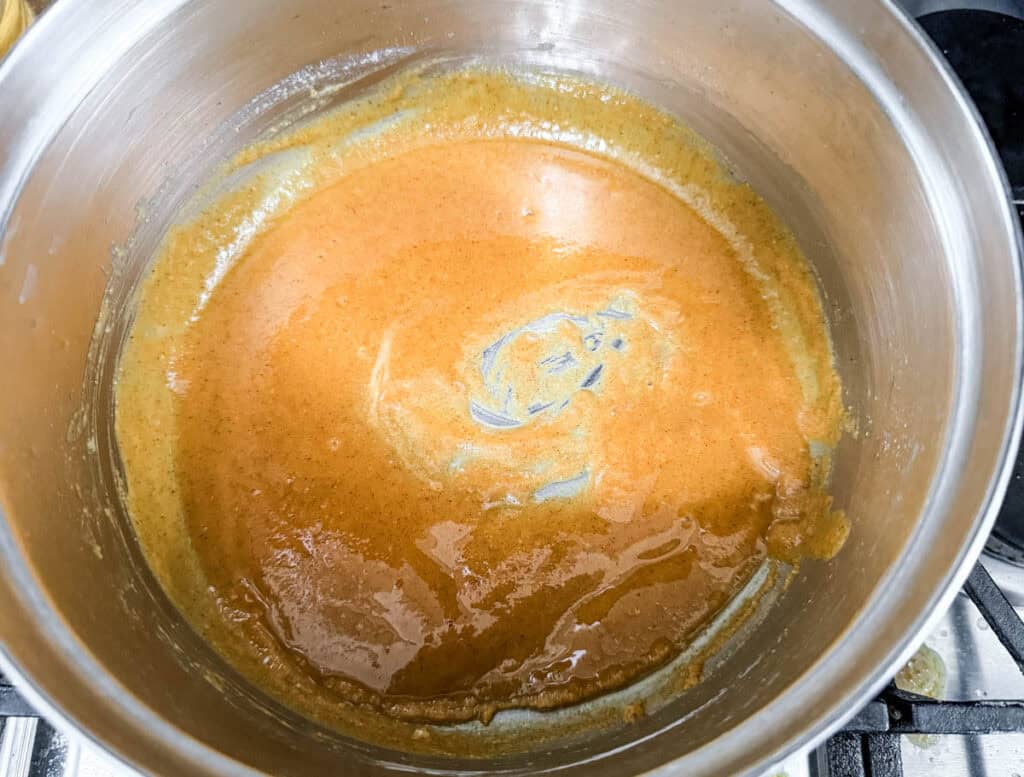 A saucepan with a smooth, brown caramel sauce swirling inside.