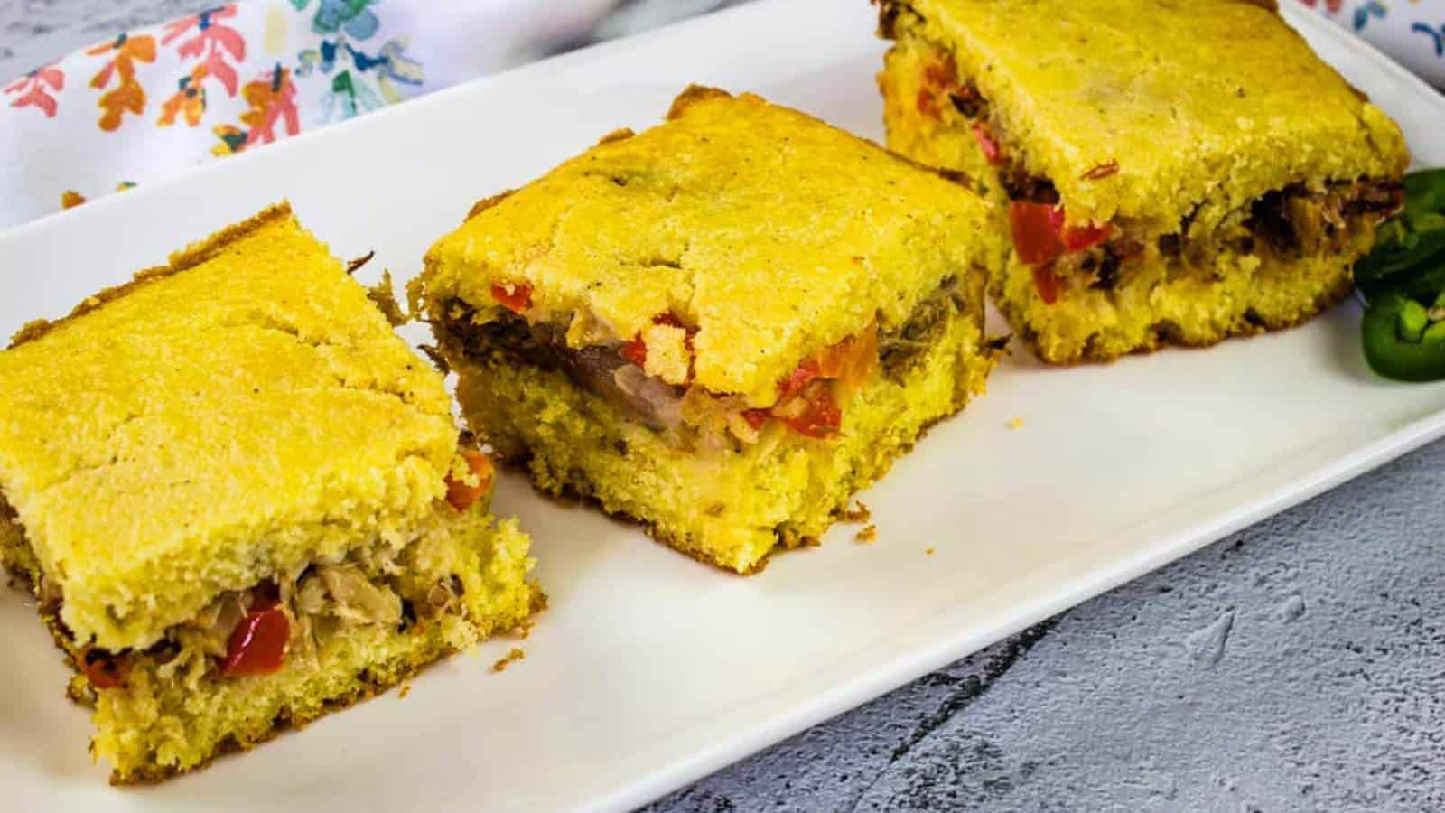 Three pieces of pulled pork stuffed cornbread on a white rectangular plate.