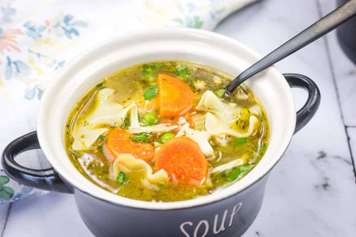 A bowl of Rotisserie Chicken Noodle Soup with a spoon resting inside.