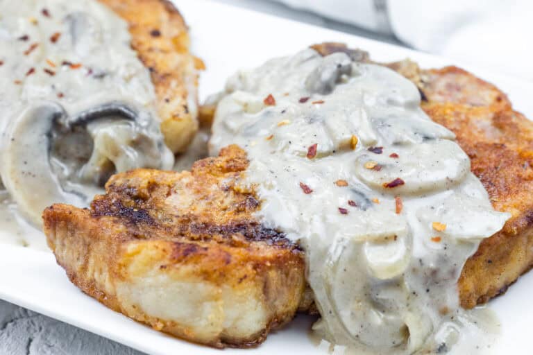 A serving of Cast Iron Smothered Pork Chops on a white plate.