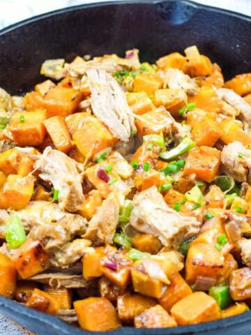 A cast-iron skillet with pulled pork and sweet potato hash.