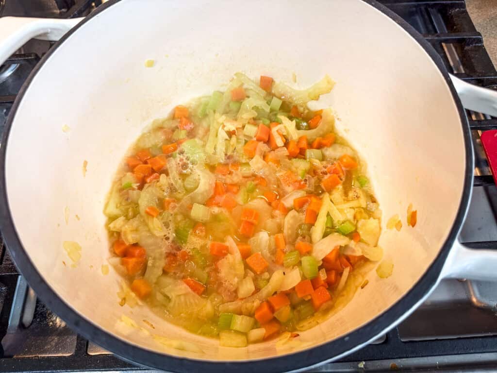 Deglazing the vegetables with the white wine in a pot.