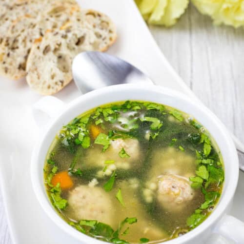 Italian Wedding Soup with meatballs, spinach, and pasta in a clear broth, served with sliced bread.