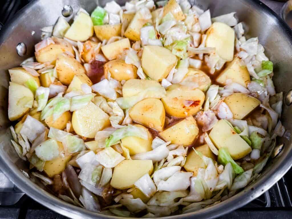 Pot with diced potatoes, cabbage, and broth, cooking on the stove.