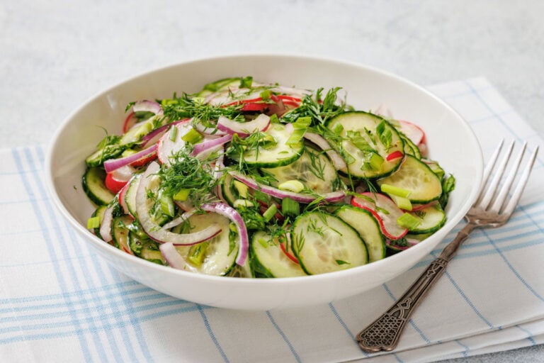 A bowl of Radish Salad containing sliced cucumbers, red onions, radishes, and fresh herbs.