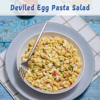 A bowl of deviled egg pasta salad on a white plate, placed on a checkered napkin with a fork. Text above reads "Deviled Egg Pasta Salad.