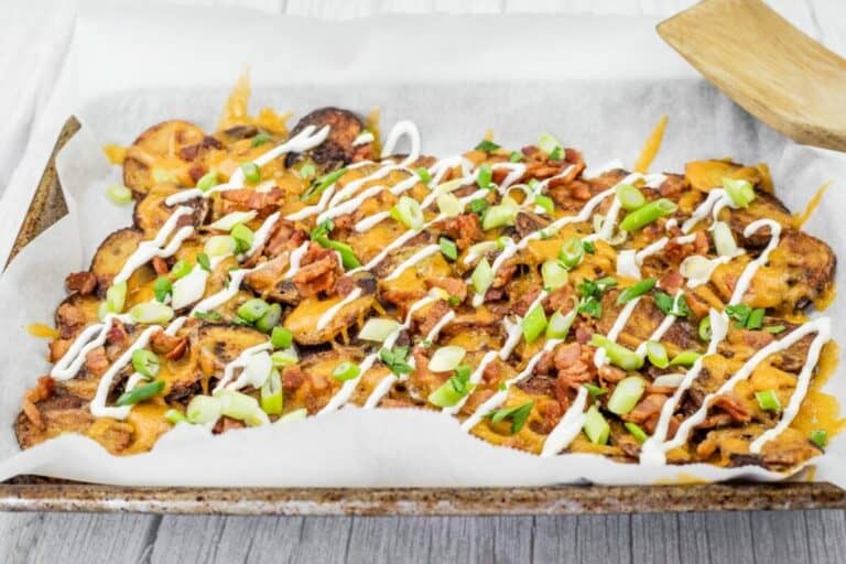 Tray of Irish nachos topped with green onions, bacon, cheese, and drizzled with sour cream.