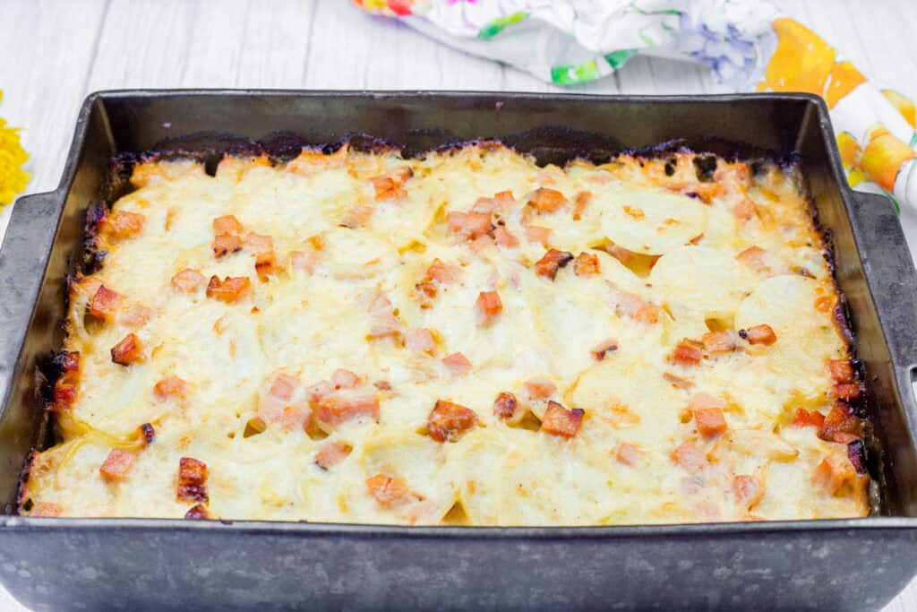 A baked dish of Scalloped Potatoes with Ham and Cheese in a rectangular metal pan.