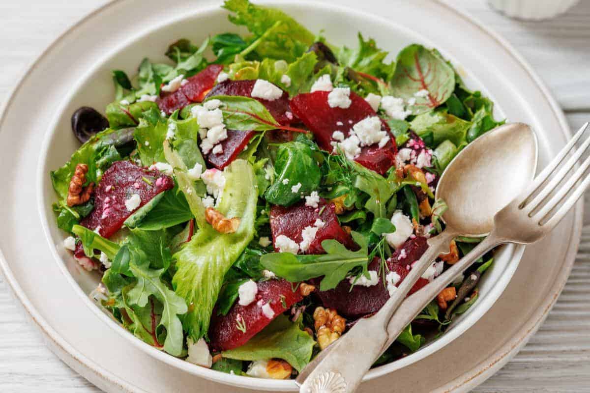 A plate of Beet Salad with Goat Cheese & Walnuts, served with a fork and spoon on the side.