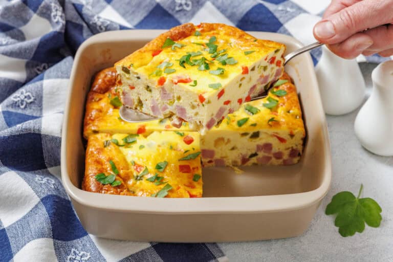 A piece of Grandma’s baked Western omelet being lifted from a square dish with a spatula.