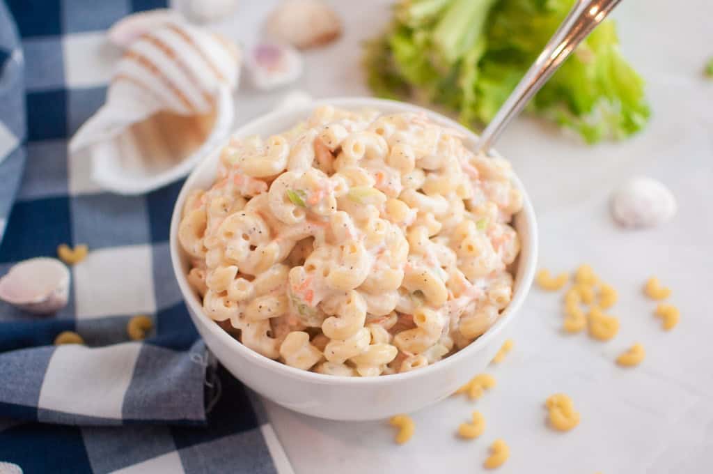 A white bowl filled Hawaiian with macaroni salad with a spoon inside.