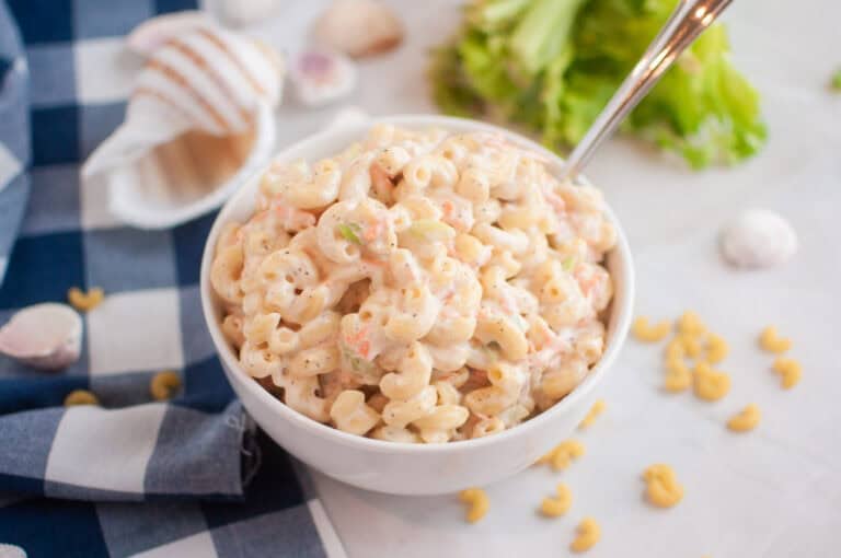 A white bowl filled with macaroni salad containing elbow macaroni and creamy dressing.