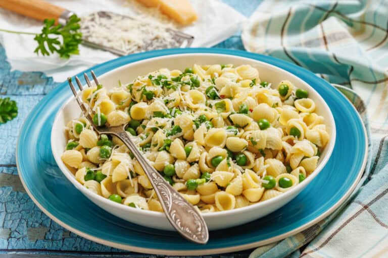 A bowl of pasta and peas with a sprinkle of cheese.