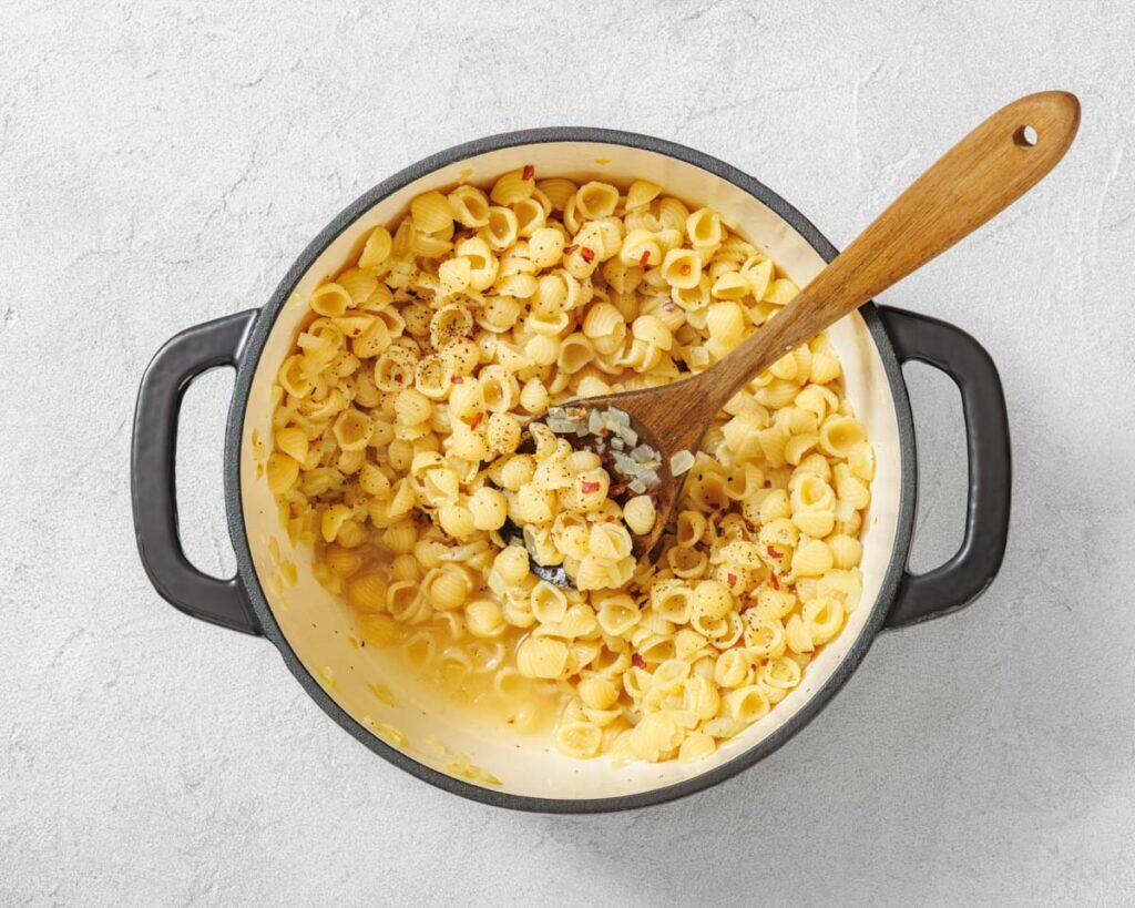 Overhead shot of macaroni and cheese in a black pot with a wooden spoon.