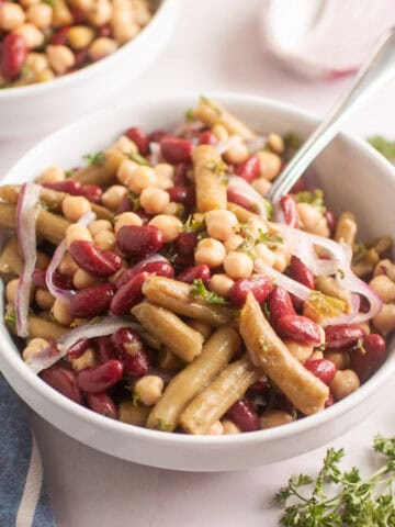 A white bowl of Three Bean Salad beside a napkin.