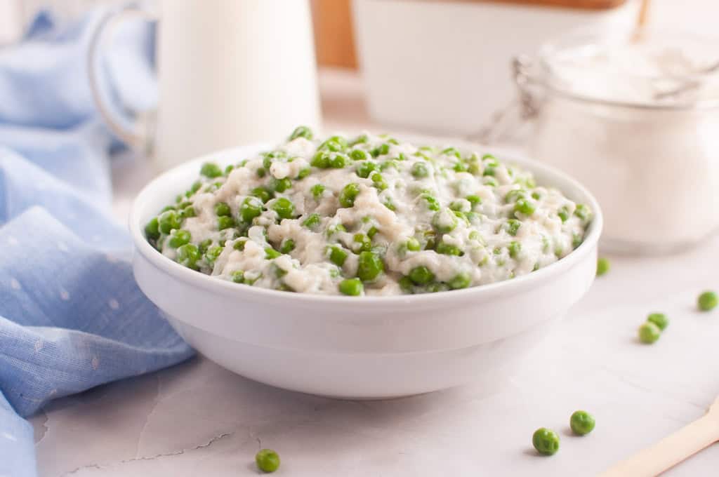 A white bowl filled with creamed peas.