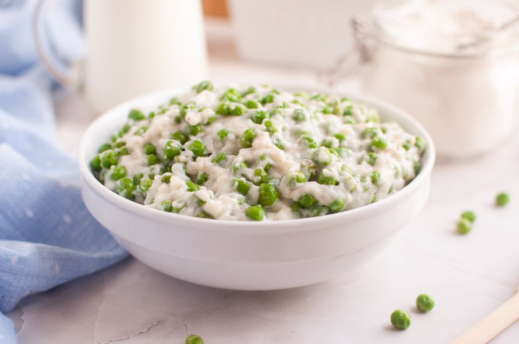 A white bowl filled with creamed peas.