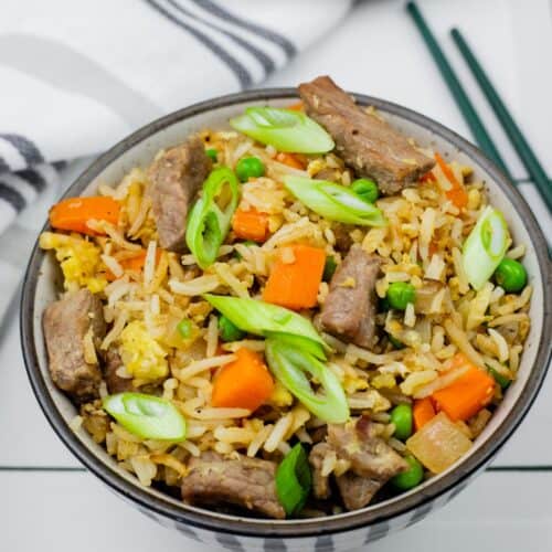 Steak fried rice with green onions and carrots in a bowl.