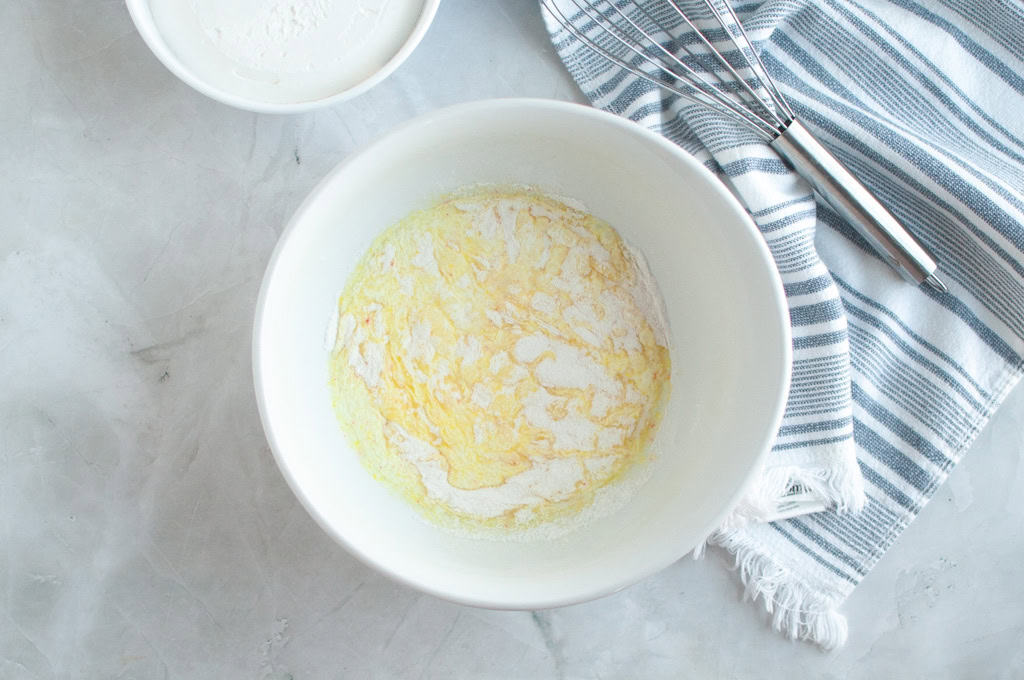 Overhead shot of whipped topping being mixed in a white bowl with a whisk.