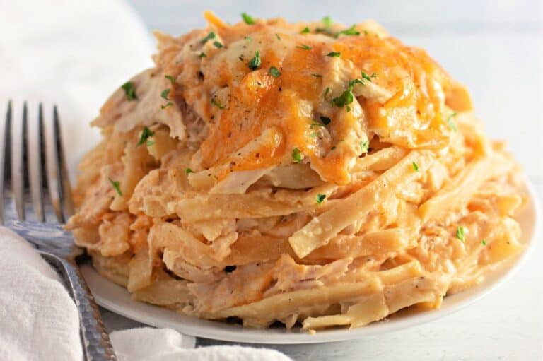 A plate of chicken tetrazzini topped with melted cheese and sprinkled with chopped herbs.