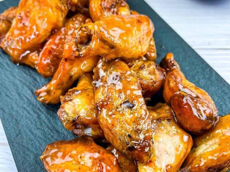 A close-up of glazed chicken wings arranged on a dark serving platter.