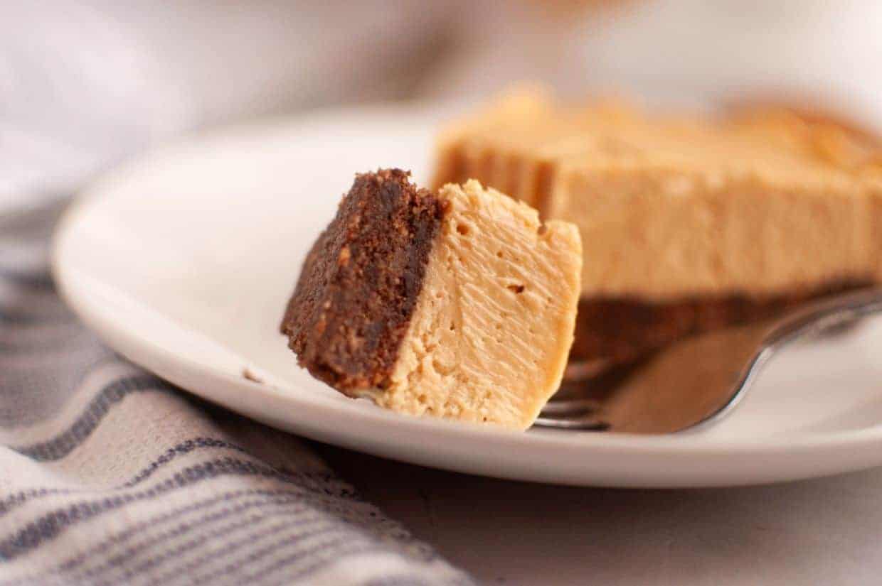 A close-up of a fork holding a bite of Peanut Butter and Chocolate Pie on a white plate.