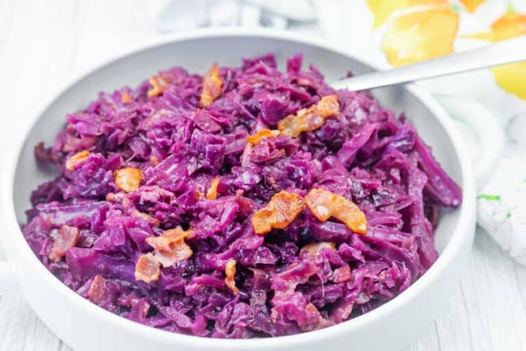 A bowl of cooked red cabbage mixed with pieces of bacon.