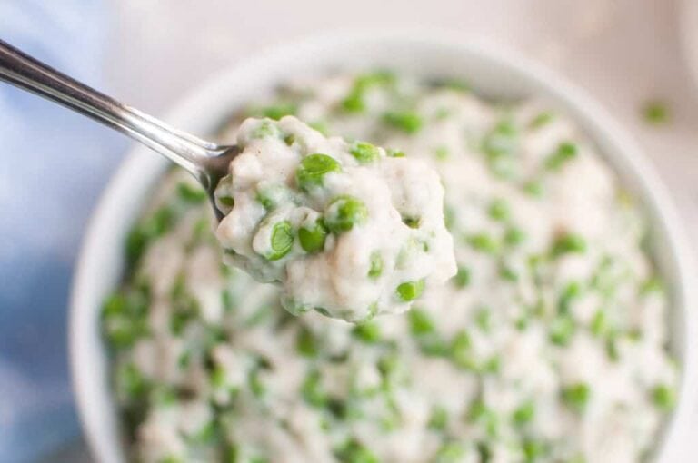 A spoonful of creamy peas held above a bowl filled with the same mixture.