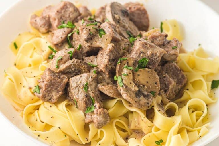 Close-up image of slow cooker beef stroganoff with noodles, beef, and herbs.